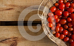 Tomates-cereja vermelhos pequenos dentro de cesta caixote de madeira em estilo rÃÂºstico, foco seletivo photo