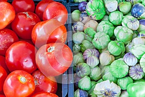 Tomatillo and red tomatoes on black plastic food crate at farmer market in Washington, America