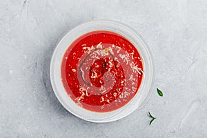 Tomato basil soup with parmesan cheese on gray stone background