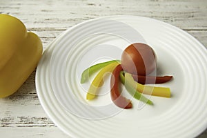 Tomato and Bulgarian red green yellow pepper slices on white plate