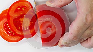 Tomato cut with a knife. Close-up. Sliced tomato. Hands using kitchen knife cutting fresh tomato