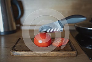 Tomato cut into several pieces with a sharp knife. Tomato lying on a wooden board. Levitation, healthy plant vegetarian food.