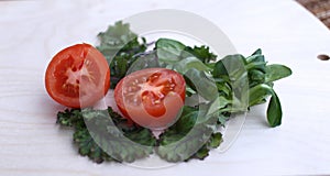 Tomato cut into two parts and spinach green fresh on white background side view