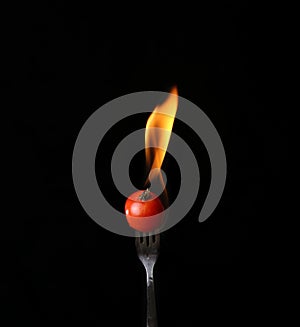 Tomato on fire with blue flames isolated on black background
