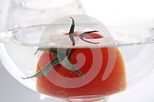 Tomato floats in water with bubbles in glass glass glass on white background