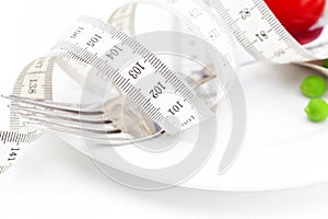 Tomato,fork ,peas and measure tape on a plate