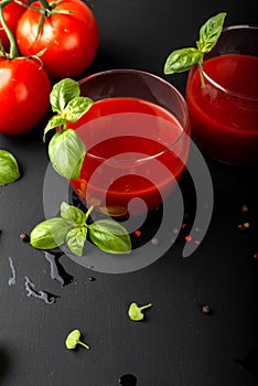Tomato fresh juice with basil and cherry tomatoes on a black background