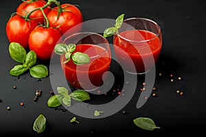 Tomato fresh juice with basil and cherry tomatoes on a black background. Close-up.