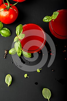 Tomato fresh juice with basil and cherry tomatoes on a black background. Top view.