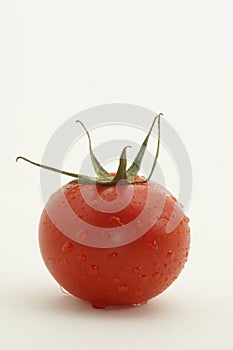 Tomato with fruitstem against white background