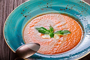 Tomato gazpacho soup with basil, feta cheese, ice and bread on d