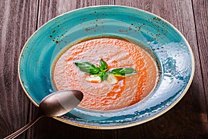 Tomato gazpacho soup with basil, feta cheese, ice and bread on dark wooden background, Spanish cuisine. Ingredients on table