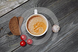 Tomato gazpacho soup with bread and garlic in white bowl on wood