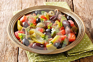 Tomato and green pepper salad with anchovies and olives close-up in a bowl. horizontal