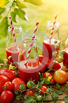 Tomato juice in glass bottles and fresh tomatoes on a wooden table