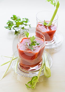 Tomato juice in the glass cup decorated with parsley and celery sticks