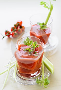 Tomato juice in the glass cup decorated with parsley and celery sticks