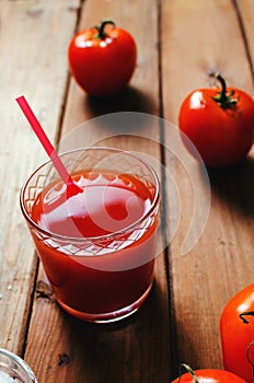 Tomato juice in glass with fresh tomatoes and salt. Rustic wooden background