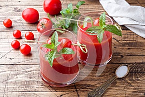 Tomato juice with mint in glass and fresh tomatoes on a wooden table. Healthy organic food concept