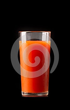 Tomato juice in a tall glass glass on a black background