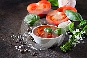 Tomato ketchup sauce in a bowl with spices, basil leaves and tomatoes