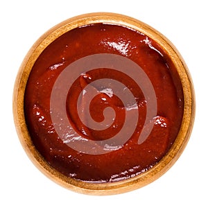 Tomato ketchup in wooden bowl over white