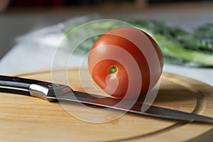 tomato and knife on the wooden cutting board