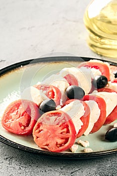 Tomato and mozzarella caprese salad with olives on gray table