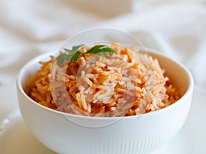 Tomato onion rice, Tamatar Biryani, jollof in white bowl on a white wooden table, horizontal, close up