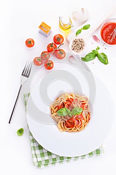 Tomato pasta spaghetti with fresh tomatoes, basil, italian herbs and olive oil in a white bowl on a white wooden background