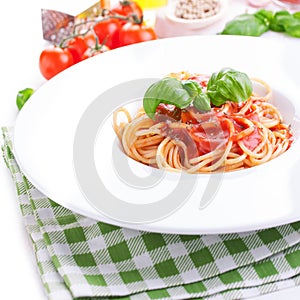 Tomato pasta spaghetti with fresh tomatoes, basil, italian herbs and olive oil in a white bowl