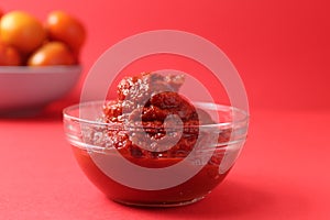 tomato paste in a glass sauce bowl on a red background monocolor. Food sauce red tomato food