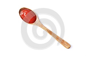 Tomato paste on a wooden spoon isolated on white