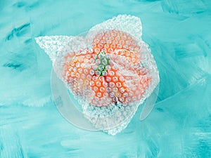 Tomato in plastic package on turquoise