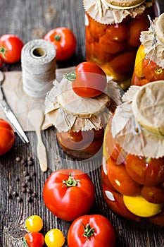 Tomato preserves in the jars, raw tomato fruits and seasonings