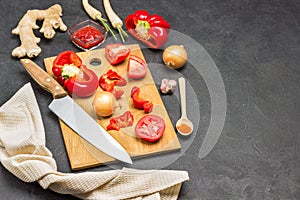 Tomato, red pepper  and knife on cutting board. Beige napkin