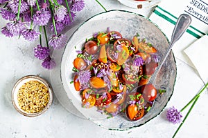 Tomato salad with chives flowers in a white bowl photo