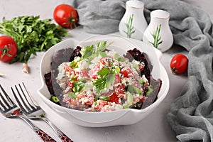 Tomato salad with cottage cheese, green onions, parsley and spices in a white bowl on gray background