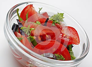 Tomato salad with green and red basil in a glass bowl