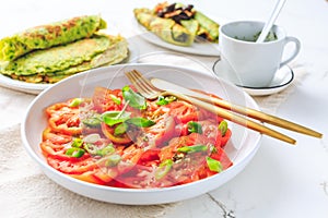 Tomato salad with onions and ramson pancakes or crepes