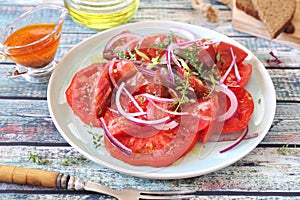 Tomato salad with red onion and spicy sauce of different varieties of tomatoes, two slices of rye bread