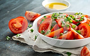 Tomato salad with spring onion and herbs in white bowl. Healthy summer food