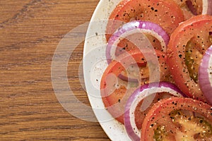 Tomato salad in a white plate on a wooden board