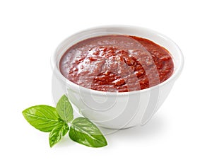 Tomato sauce and basil in a white bowl against a white background