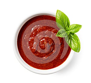 Tomato sauce and basil in a white bowl against a white background
