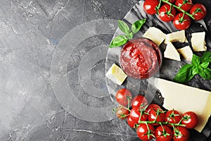 Tomato sauce in a bowl, chunks of Parmesan cheese, fresh green basil