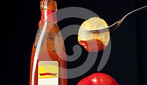 Tomato sauce in a glass bottle, chips on a fork