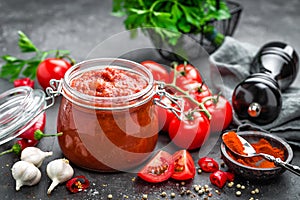 Tomato sauce in glass jar and fresh tomatoes