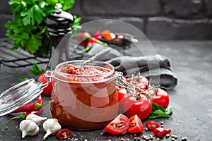 Tomato sauce in glass jar and fresh tomatoes