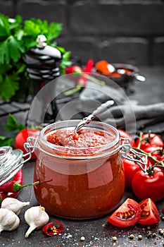 Tomato sauce in glass jar and fresh tomatoes